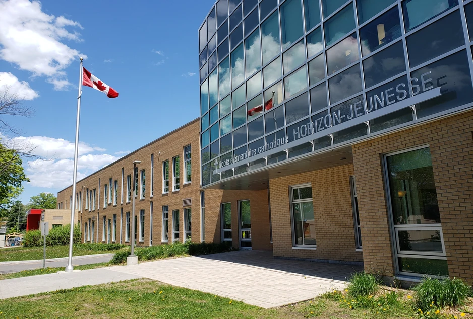 L'École élémentaire catholique Horizon-Jeunesse, avec son entrée vitrée sur deux étages et le drapeau canadien qui flotte devant.