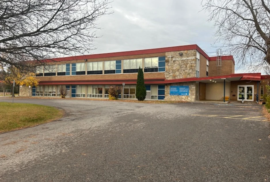 L'École élémentaire catholique Lamoureux vue de son stationnement : un bâtiment de deux étages à toit rouge, avec une croix près de l'entrée.